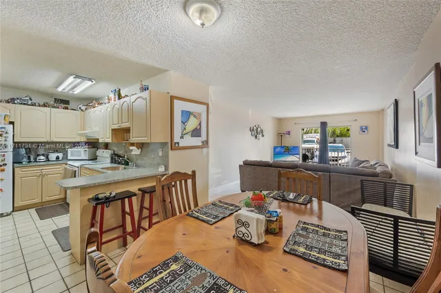a living room with stainless steel appliances furniture a rug and a kitchen view