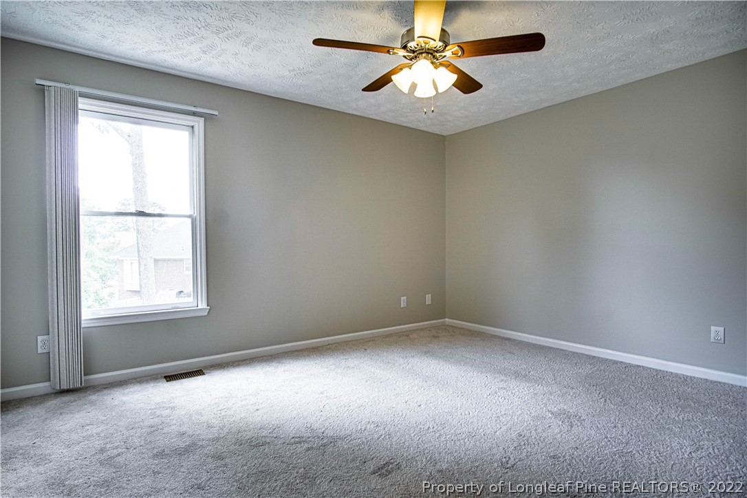 1810 Nuthatch Road Fayetteville, NC 28304 - Photo 21 of 37 an empty room with a chandelier fan and windows