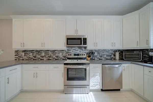 a kitchen with white cabinets and refrigerator