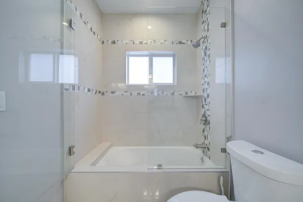 a bathroom with a granite countertop sink a toilet a mirror and shower
