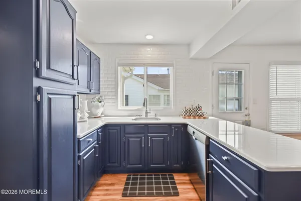 a kitchen with stainless steel appliances kitchen island granite countertop a refrigerator a stove a sink a dining table and chairs with wooden floor