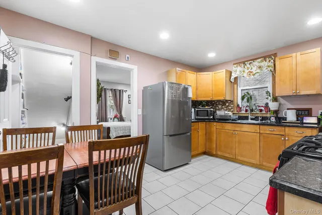 a kitchen with stainless steel appliances granite countertop a refrigerator a sink a stove a dining table and chairs