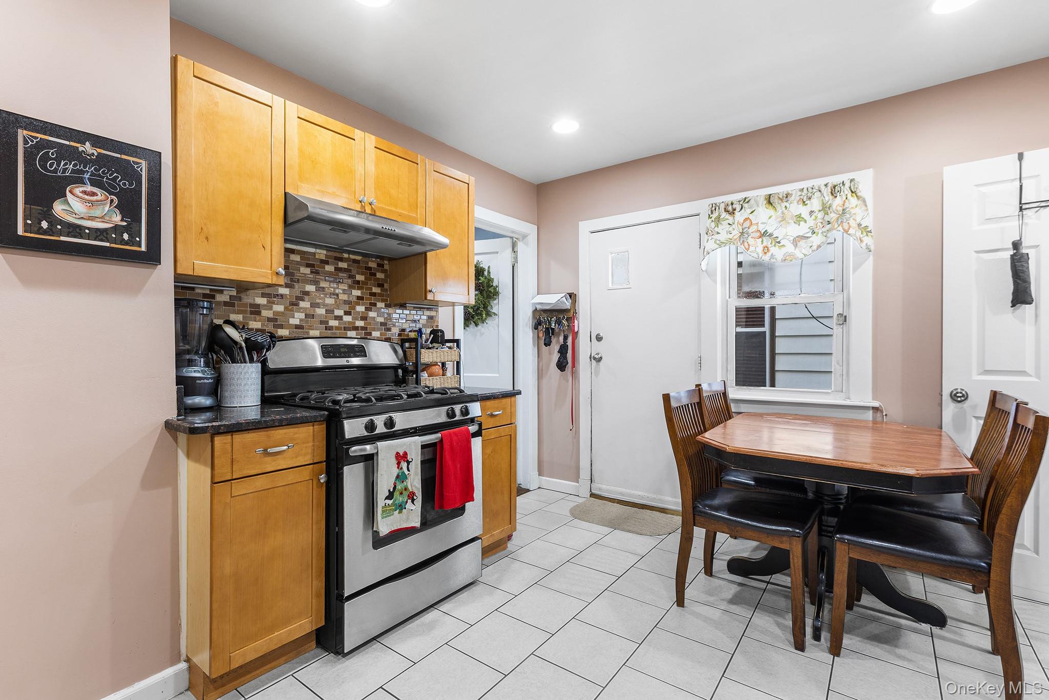 42 Warren Street New Rochelle, NY 10801 - Photo 5 of 14 a kitchen with stainless steel appliances granite countertop a stove a refrigerator a dining table and chairs