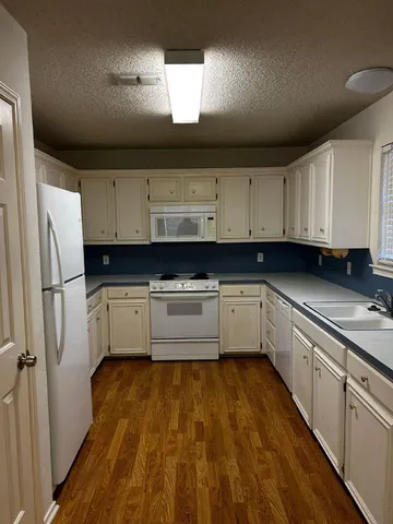 a kitchen with granite countertop a cabinets and white appliances