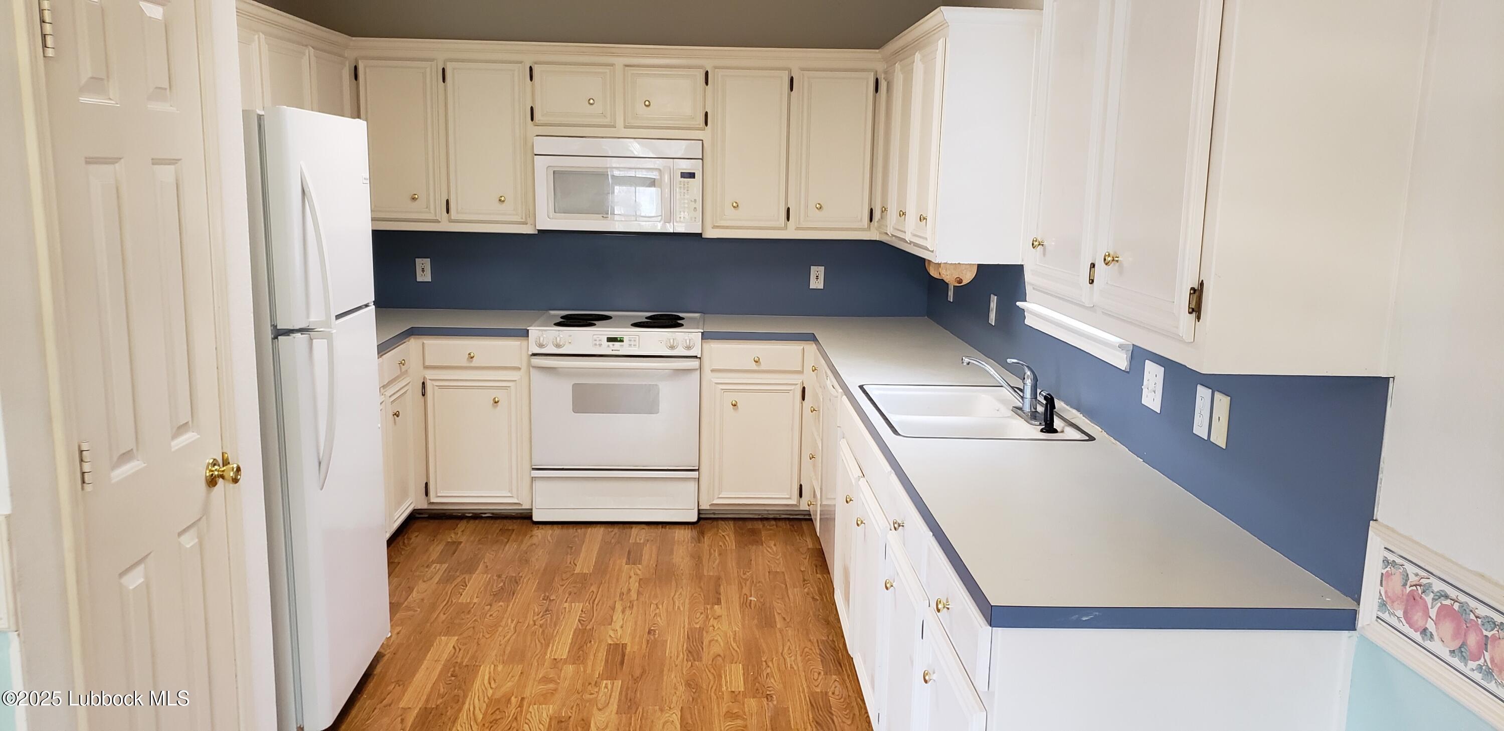 6220 7th Street Lubbock, TX 79416 - Photo 3 of 28 a kitchen with wooden cabinets and white appliances