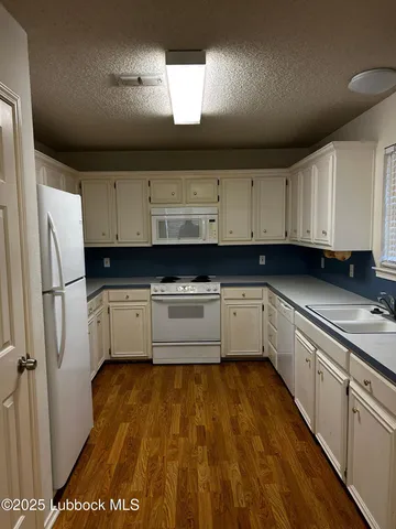 a kitchen with granite countertop a cabinets and white appliances