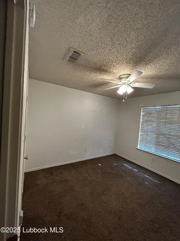 an empty room with a ceiling fan and a window