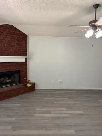 a view of empty room with wooden floor and fireplace