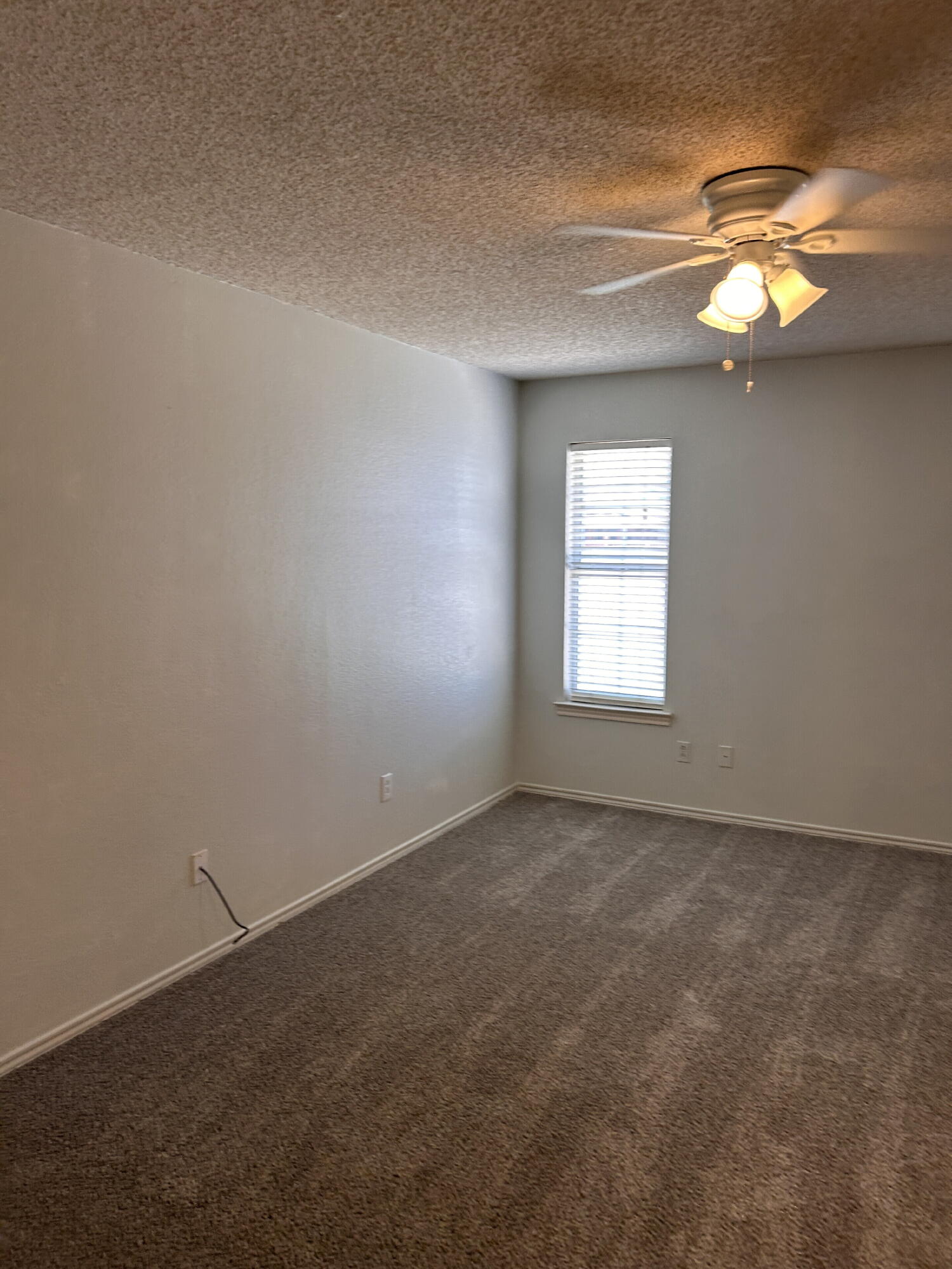 6220 7th Street Lubbock, TX 79416 - Photo 8 of 17 an empty room with a chandelier fan and windows