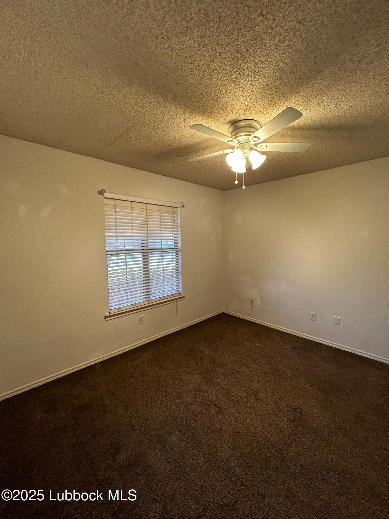6220 7th Street Lubbock, TX 79416 - Photo 9 of 28 an empty room with a ceiling fan and a window