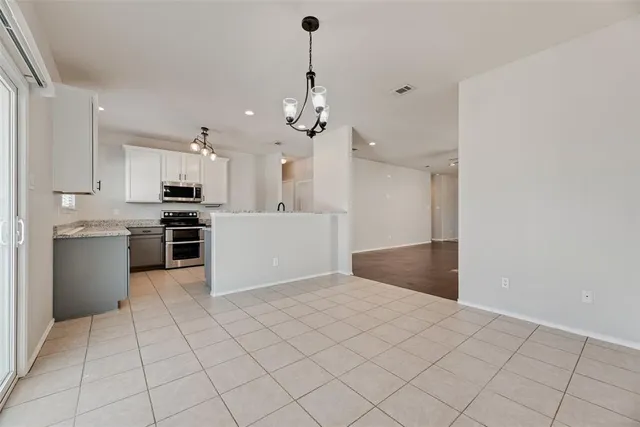 a kitchen with kitchen island granite countertop a refrigerator a stove a sink and white cabinets