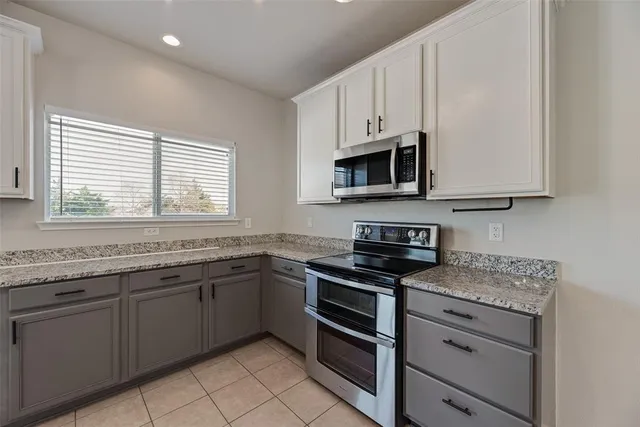 a kitchen with stainless steel appliances granite countertop white cabinets granite counter tops and a window