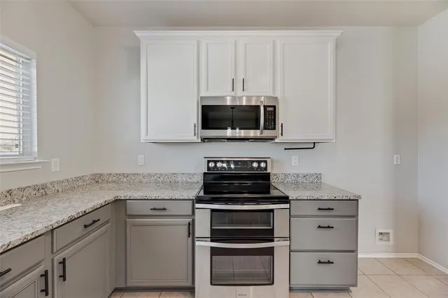 a kitchen with granite countertop white cabinets and stainless steel appliances