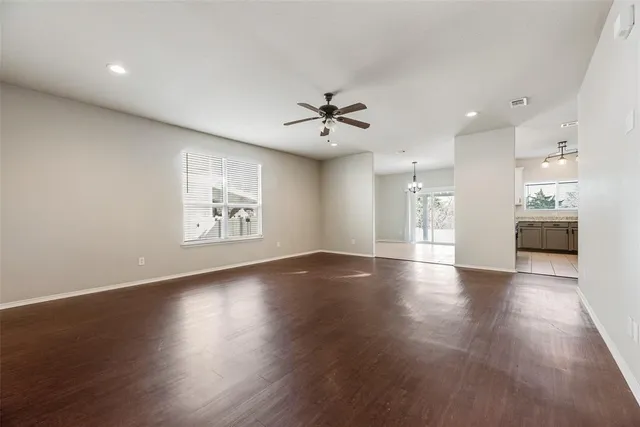 an empty room with wooden floor and a kitchen