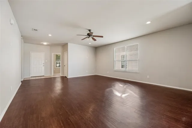 a view of an empty room with a window and wooden floor