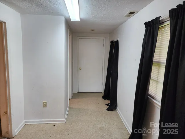 an empty room with wooden floor and fan
