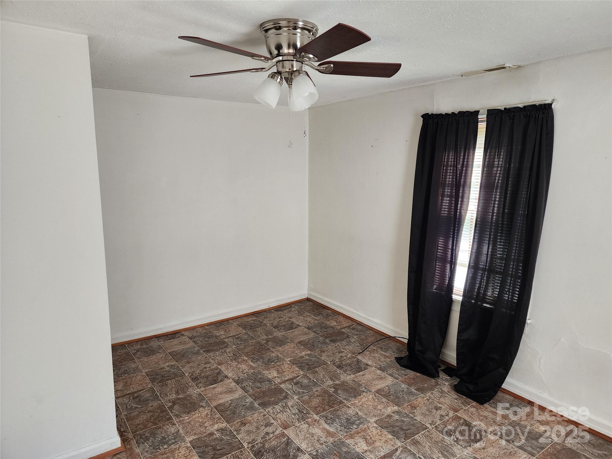 435 Rankin Street Northwest Lenoir, NC 28645 - Photo 3 of 10 an empty room with wooden floor and fan