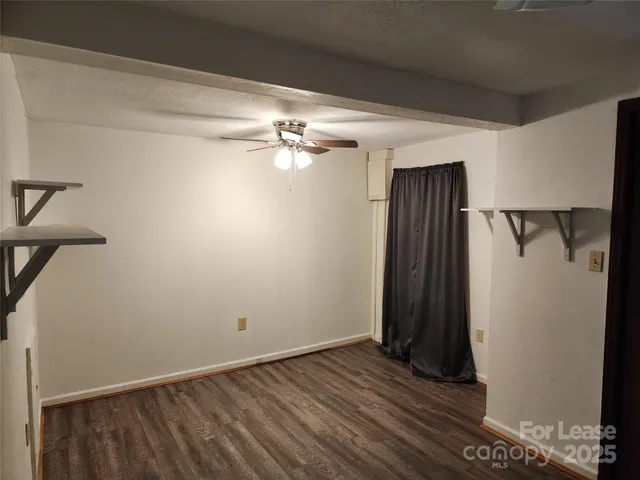 an empty room with wooden floor and a ceiling fan
