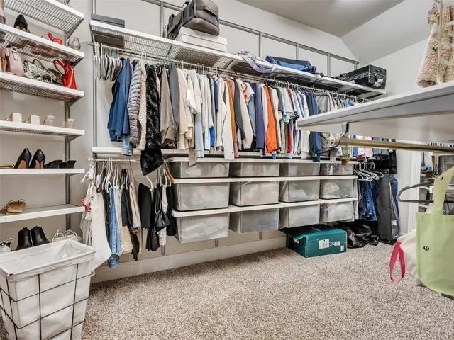 a view of walk in closet with clothes and shoes