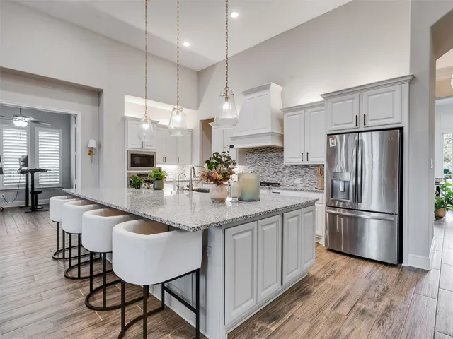 a kitchen with stainless steel appliances a dining table chairs refrigerator and sink