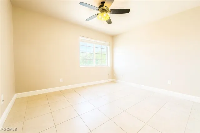 a view of an empty room and window with a ceiling fan