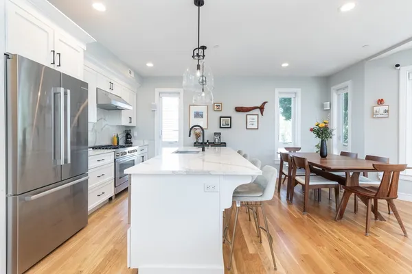 a kitchen with stainless steel appliances a dining table chairs stove refrigerator and cabinets