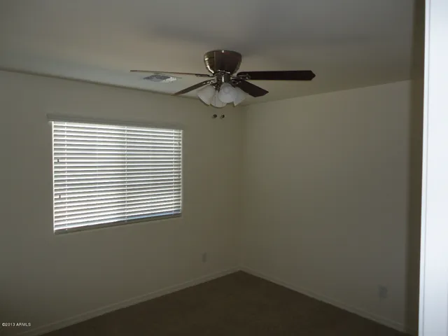 an empty room with a window and a fan
