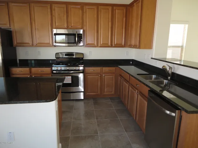 a kitchen with stainless steel appliances granite countertop a stove a sink and a microwave