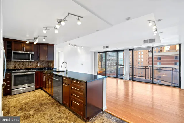 a large kitchen with stainless steel appliances granite countertop a stove and cabinets with wooden floor