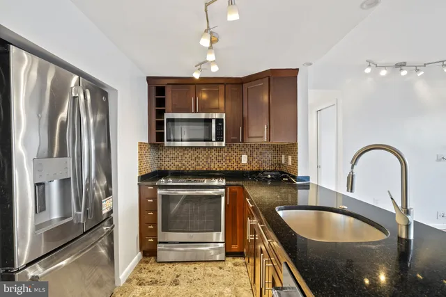 a kitchen with granite countertop a stove sink and refrigerator