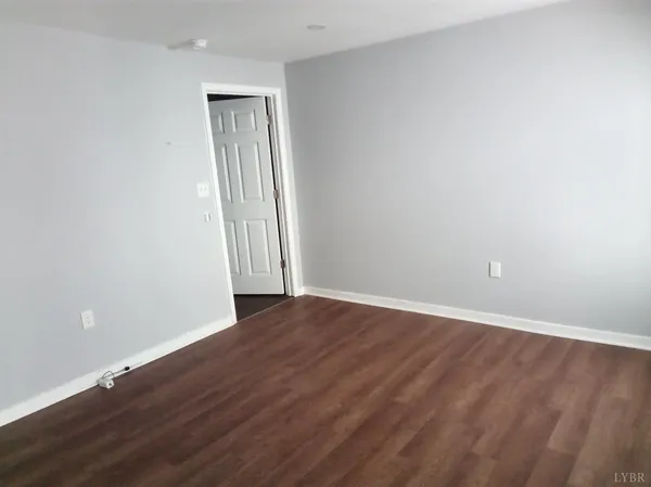 a view of an empty room with wooden floor and closet