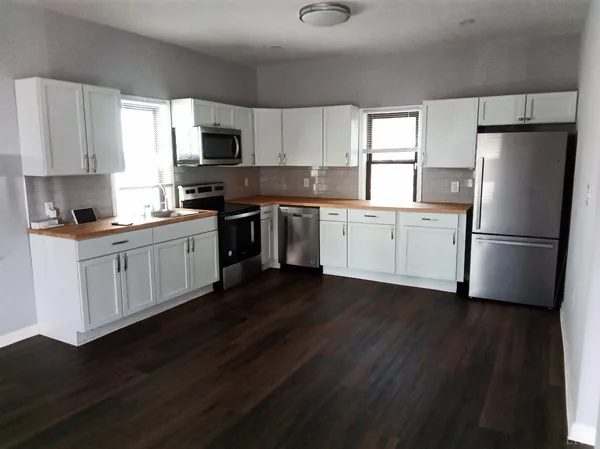 a kitchen with a sink wooden floor and stainless steel appliances