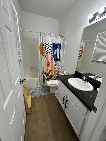 a bathroom with a granite countertop sink a mirror and shower