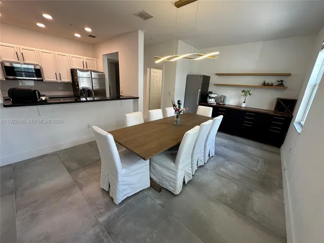 a kitchen with stainless steel appliances kitchen island granite countertop a stove a sink a microwave a refrigerator and cabinets