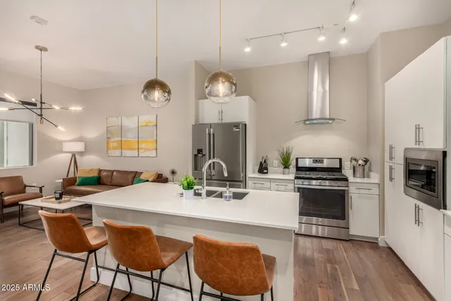 a kitchen with stainless steel appliances granite countertop a stove a sink dishwasher a kitchen island with wooden cabinets and floor