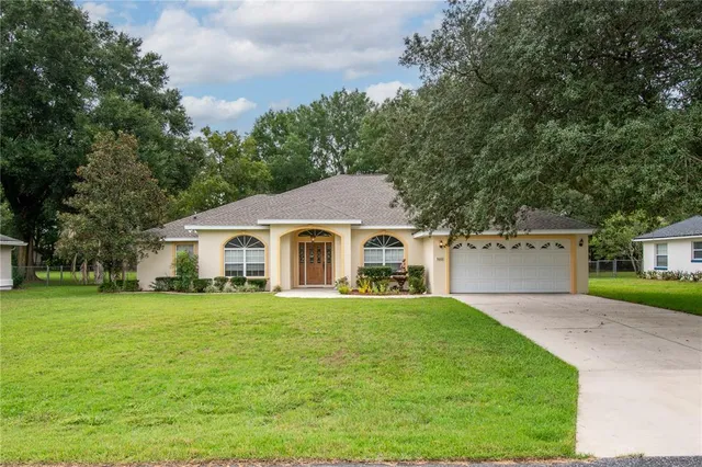 a front view of a house with a yard and trees