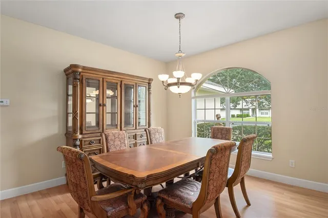 a view of a dining room with furniture a chandelier and large windows