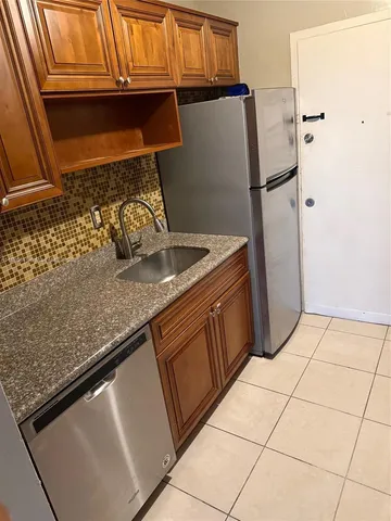 a kitchen with granite countertop a sink and a refrigerator