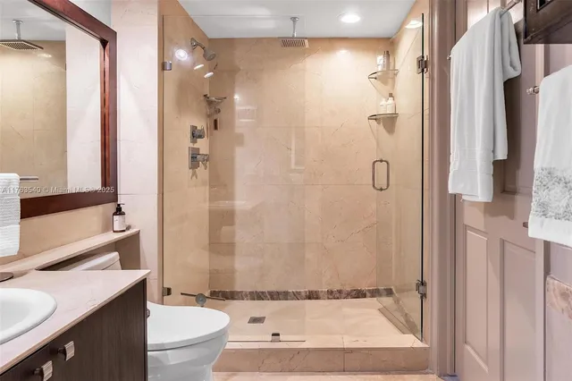 a bathroom with a granite countertop shower sink vanity mirror and toilet