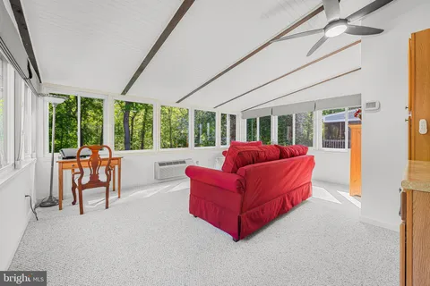 a living room with furniture a ceiling fan and a large window