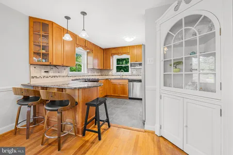 a kitchen with stainless steel appliances granite countertop a stove top oven a sink a dining table and chairs with wooden floor