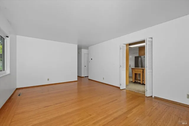 a view of an empty room with wooden floor and closet