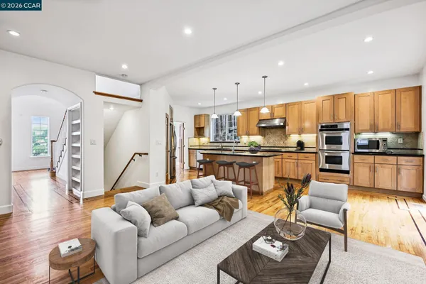 a living room with furniture kitchen and a wooden floor