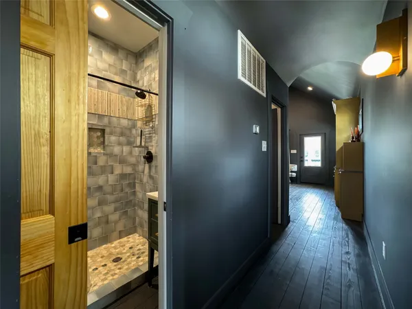 a view of hallway with wooden floor and a bathroom