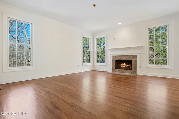 a view of an empty room with wooden floor windows and a fireplace