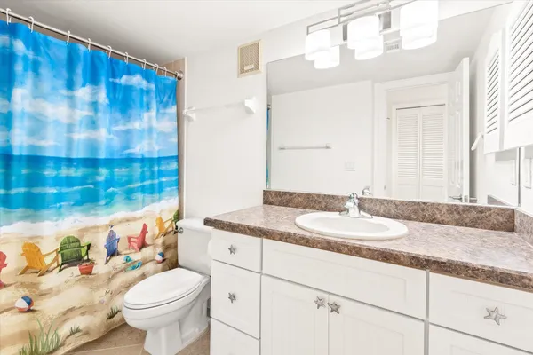 a bathroom with a granite countertop sink mirror vanity and toilet