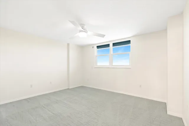 an empty room with a window and a ceiling fan