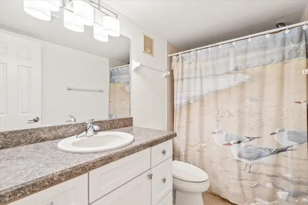 a bathroom with a granite countertop sink a toilet and a mirror