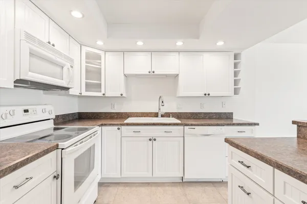 a kitchen with granite countertop white cabinets white stainless steel appliances with a sink and dishwasher