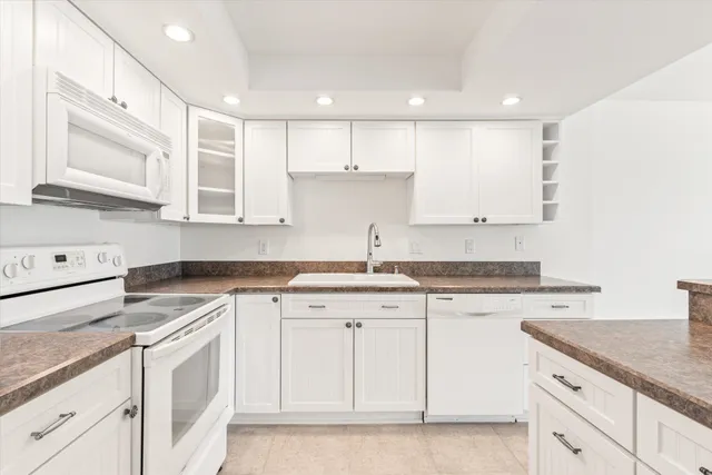 a kitchen with granite countertop white cabinets white stainless steel appliances with a sink and dishwasher